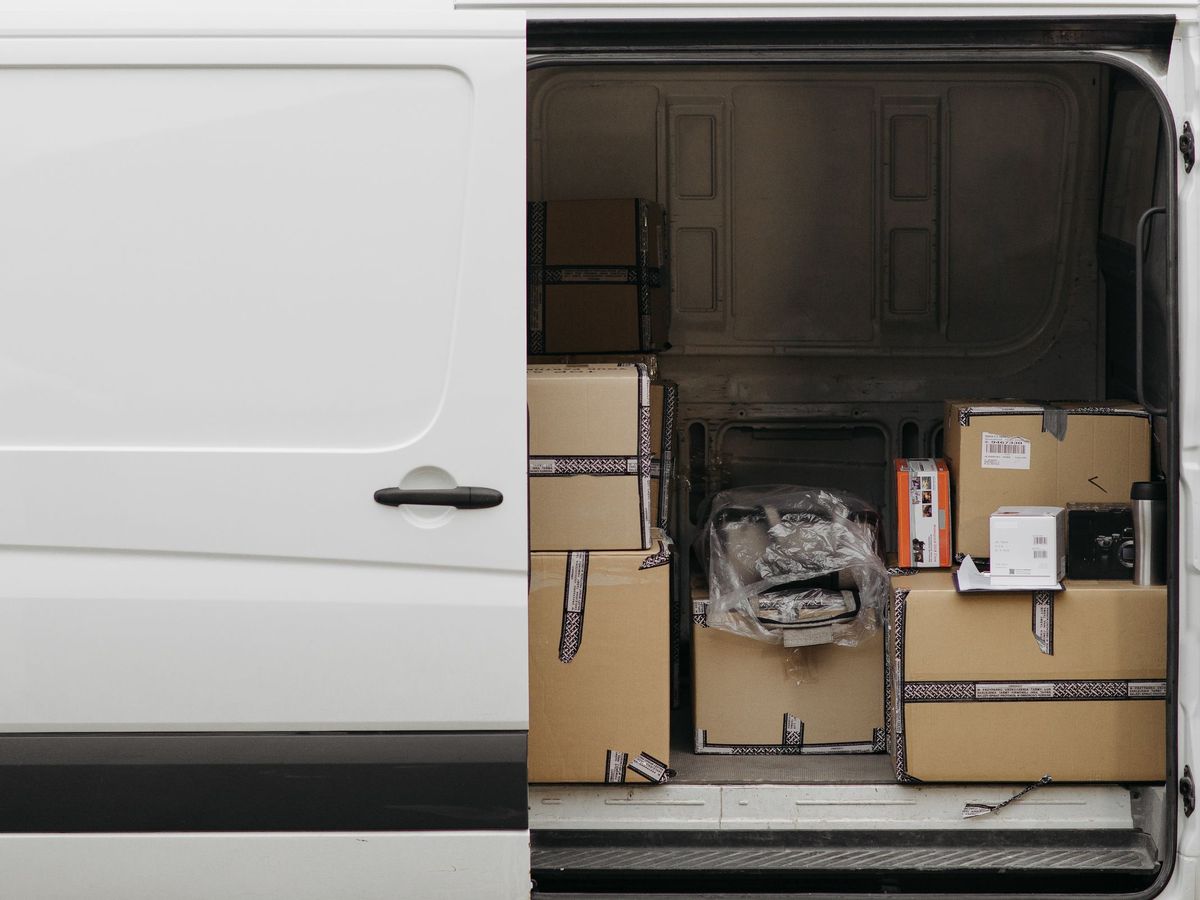 Laderaum eines weißen Transporters voller Kartons, Seitentür geöffnet
