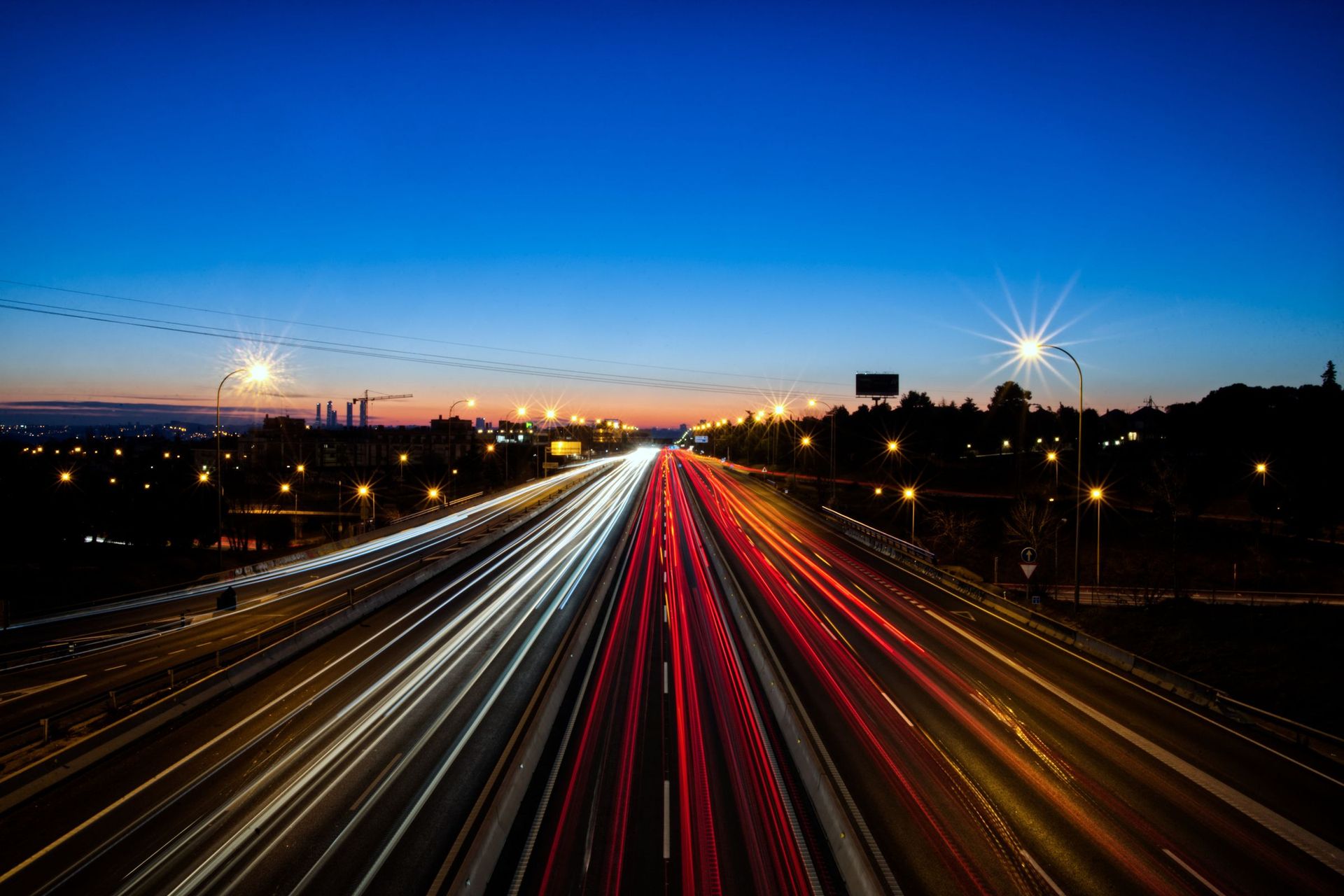 Mehrspurige Autobahn in der Dämmerung mit Lichtspuren der Scheinwerfer